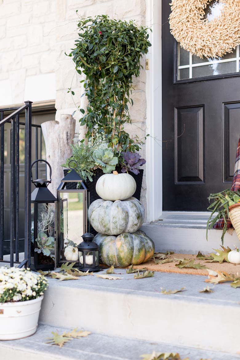 small front porch decorating ideas - giant green gords, black lanterns (they are trendy!), green bushes, purple kale, and a few sunflowers work in unison to complete this easy fall porch decor project. #frontporchideas #outdoorfalldecoratingideas #smallfrontporchdecoratingideas