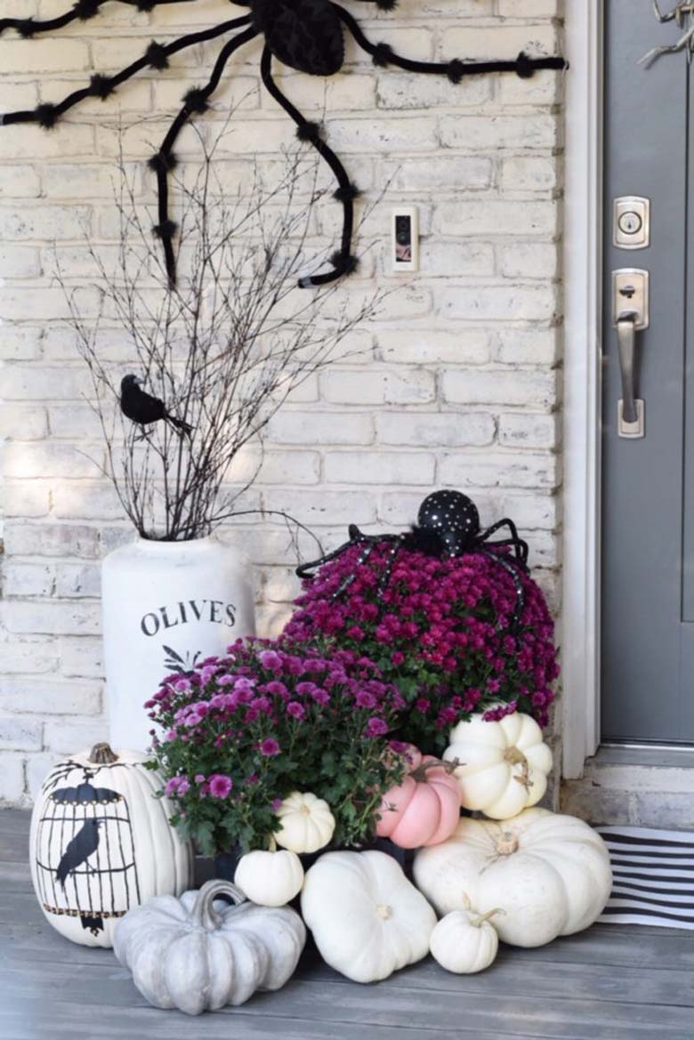 small front porch decorating ideas - pink Fall and Halloween porch decor with white and pink pumpkins paired with grey weathered gords, white over-sized vases, simple tree branches, a giant spider, and some black birds silhouettes #frontporchideas #outdoorfalldecoratingideas #smallfrontporchdecoratingideas